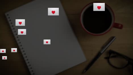 sobre múltiple con icono de corazón flotando contra el libro, la taza de café y los vasos en la superficie de madera