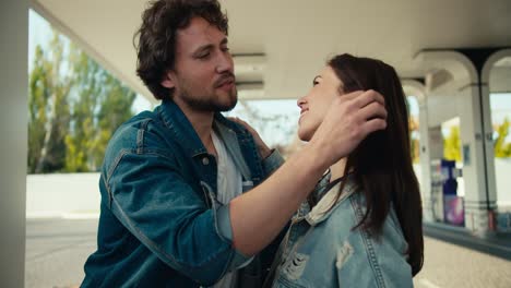 shooting up close: a brunette guy and a brunette girl in denim jackets flirt and chat at a gas station