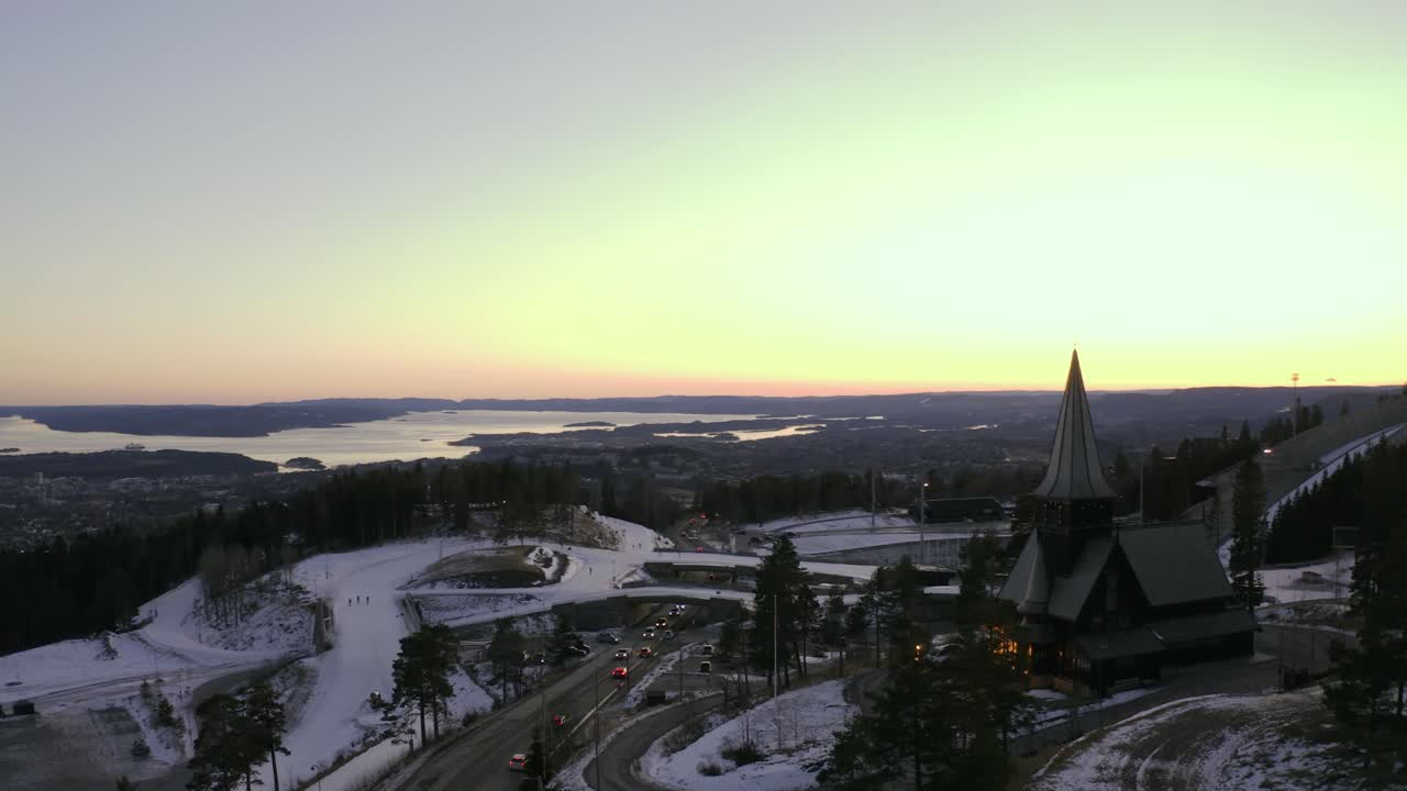 오슬로 도시 무인 항공기는 holmenkollbakken 스키 점프, oslo vinterpark winterpark tryvann at sunset과 함께 holmenkollen 예배당 교회를 감싸고 있습니다.
