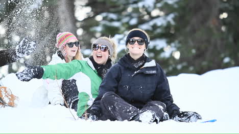 young women on a ski slope toss snow in the air