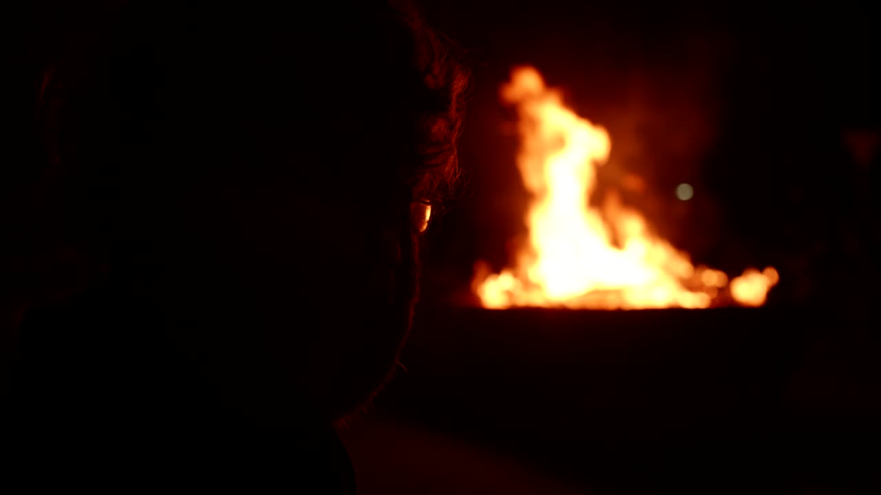 Silhouette of a Person Watching Fire in the Dark