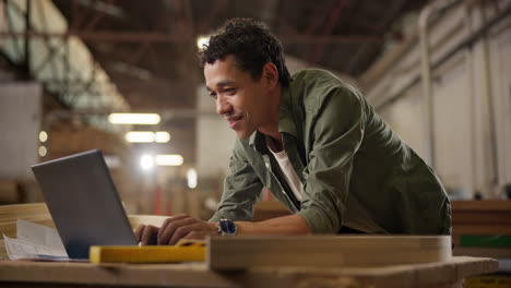 man using laptop in woodshop
