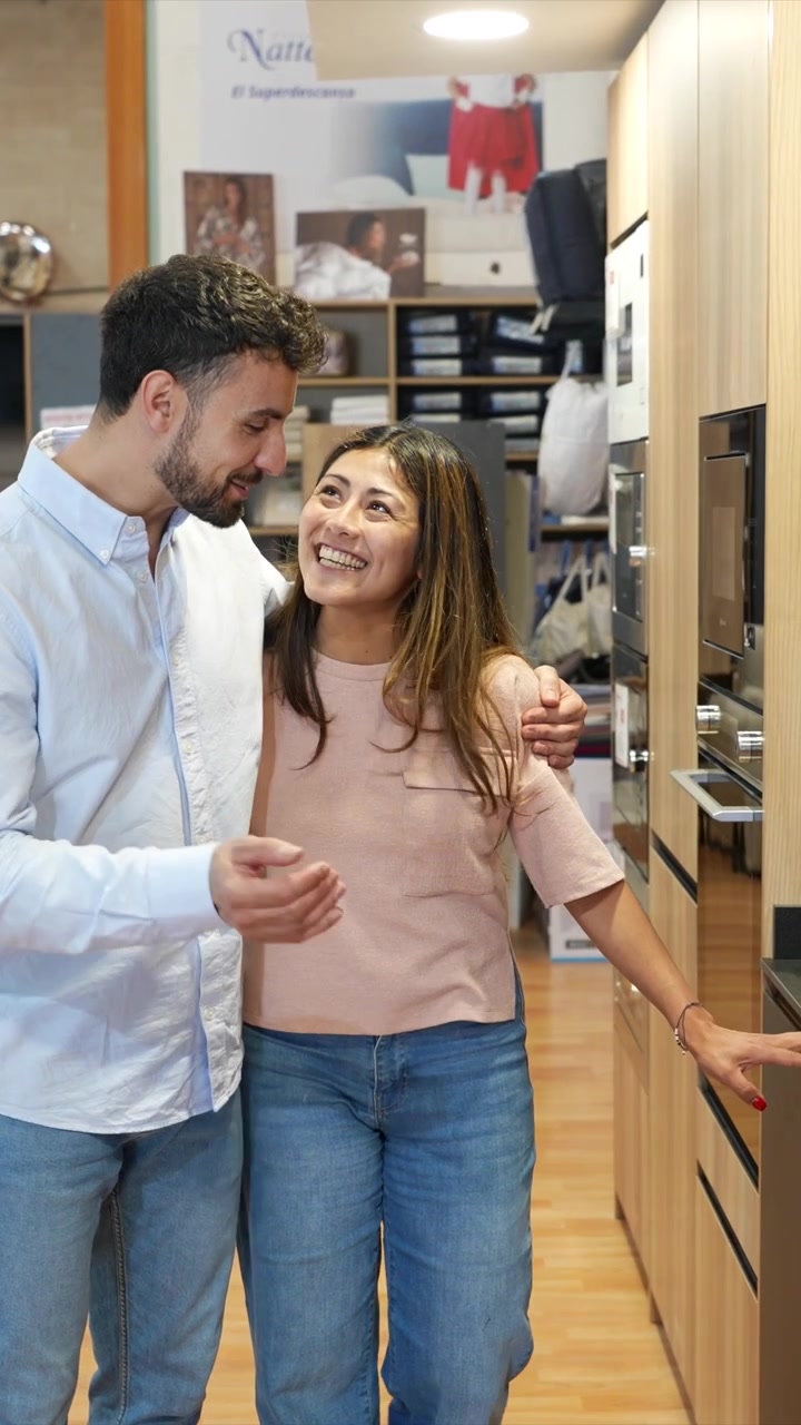Coppia felice che esamina cucine moderne in uno showroom