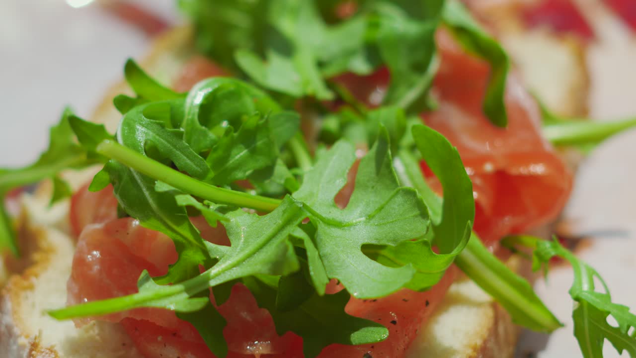 Delicious Freshly Sliced Bread with Smoked Salmon Topped with Rocket Salad and Seasoned with Cracked Black Pepper. High Quality Fresh Healthy Seafood.