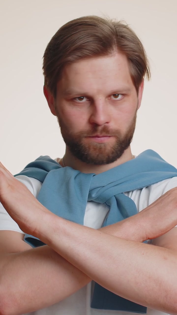 Young man say no hold palm folded crossed hands in stop gesture warning of finish prohibited access