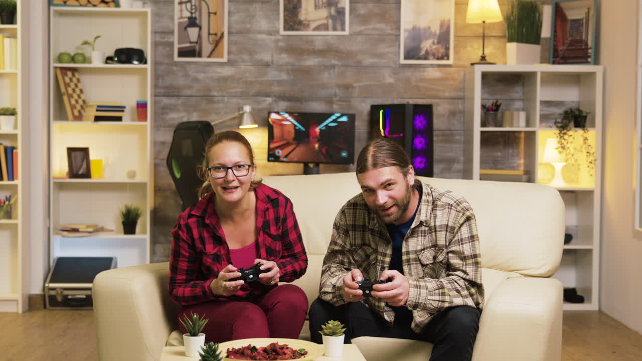 una pareja jugando videojuegos en el sofá.