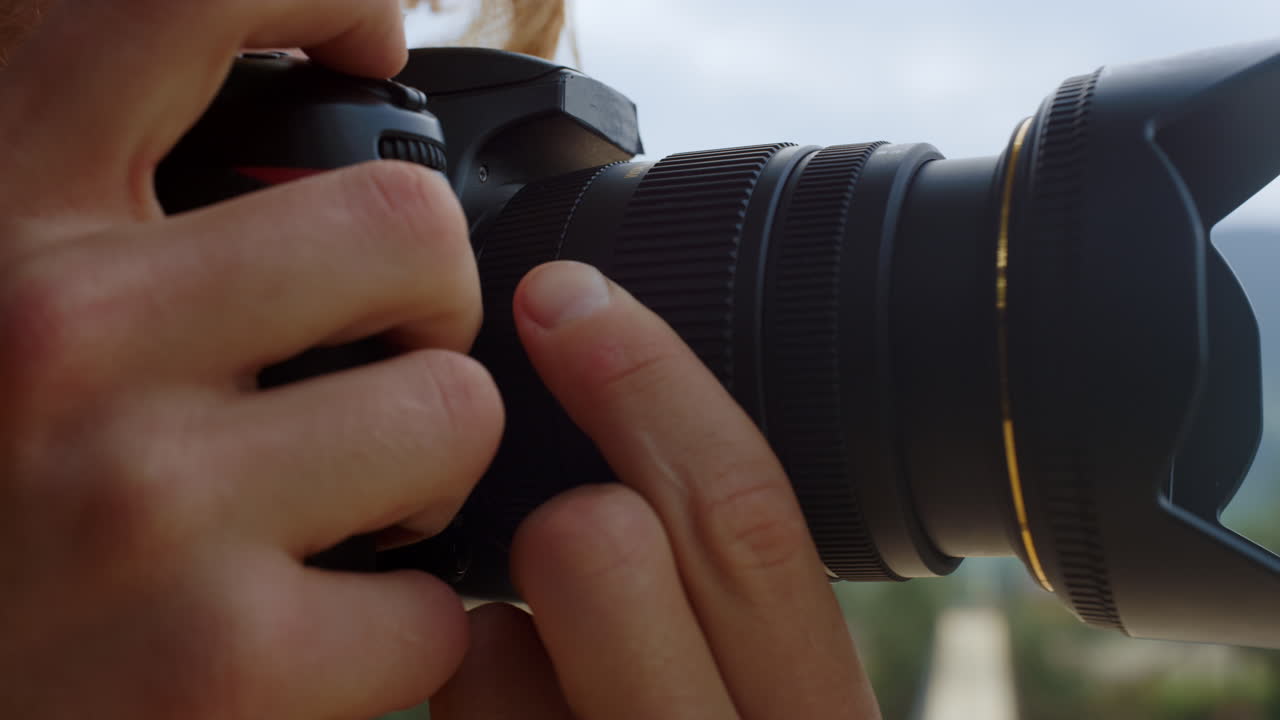 Mãos de fotógrafo com câmera tiram foto. Blogueiro em close-up fotografa ao ar livre.