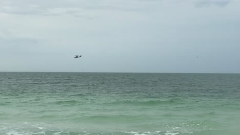 Three-small-sea-planes-flying-over-the-ocean-near-the-shore