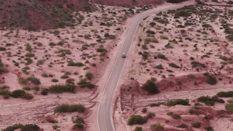 A-drone-following-the-road-with-a-car-in-Quebrada-de-las-Conchas,-Salta-Argentina