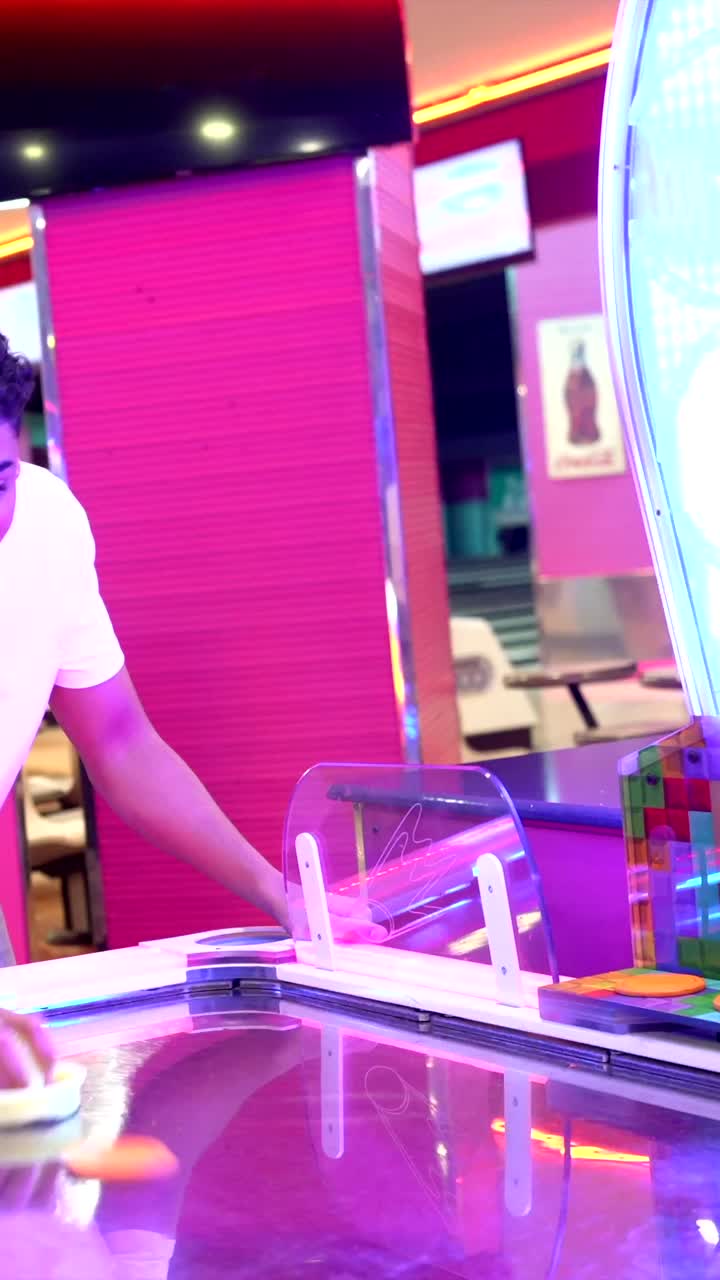 Giovani che giocano a air hockey in sala giochi