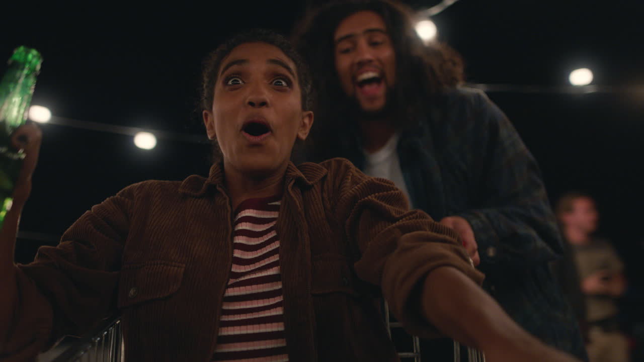 hermosa mujer joven divirtiéndose sentada en un carrito de compras grupo de amigos disfrutando de una loca fiesta en la azotea por la noche celebrando juguetón el fin de semana