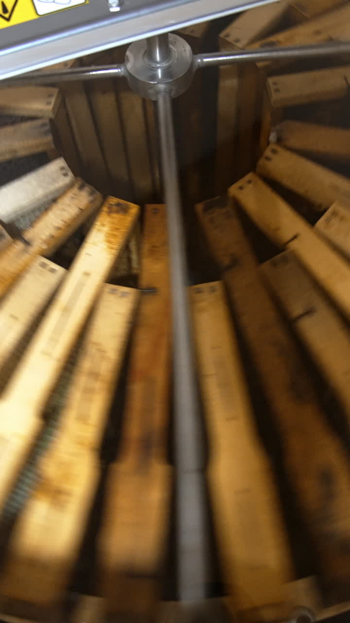 Frames with honeycombs rotating in the centrifuge device for removing honey. Harvest season at bee farm. Close up. Vertical video