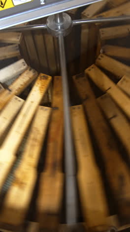 frames with honeycombs rotating in the centrifuge device for removing honey. harvest season at bee farm. close up. vertical video