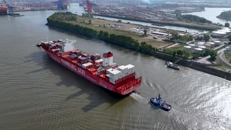 aerial capture of a huge cargo ship cruising through the calm waters in the channel near the dockyard