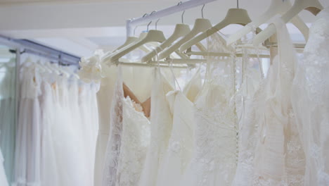 close up of beautiful bridal wedding dresses hanging on rail in shop