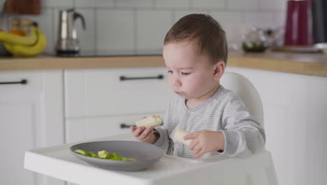 Lindo-Bebé-Comiendo-Plátano-Sentado-En-Una-Silla-Alta-En-La-Cocina-2