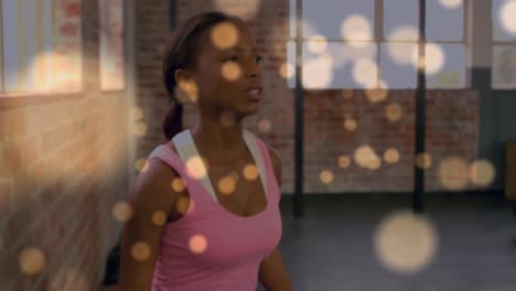 Animation-Von-Lichtflecken-über-Einer-Afroamerikanischen-Frau,-Die-Im-Fitnessstudio-Gewichte-Hebt