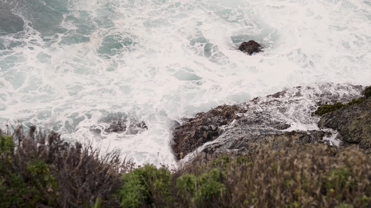 agua de mar agitada golpeando rocas en la bahía de monterey california - mirando hacia el acantilado