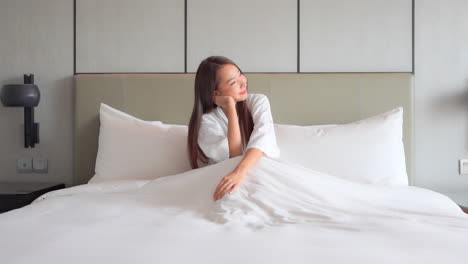 A-pretty-young-woman-sitting-up-in-bed-enjoying-the-morning