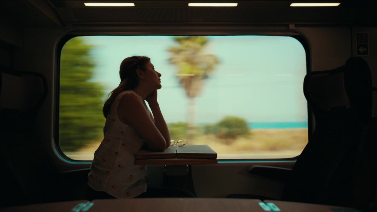 Silhouette di una donna seduta che viaggia su un treno passeggeri, vista dal finestrino