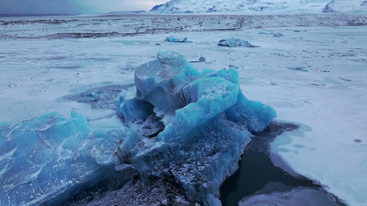 Aerial landscape view over icebergs on the frozen Jokulsarl&oacute;n lake surface, in Iceland, at dusk