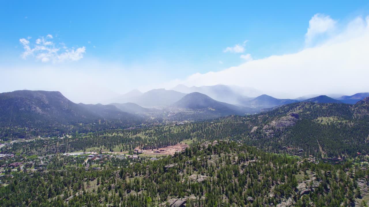 Filmato aereo 4K realizzato con drone di verdi colline alpine con maestosa catena montuosa sullo sfondo durante la splendida stagione estiva