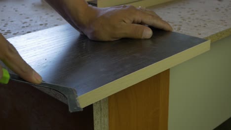 close-up view of a carpenter cutting and fitting the edge of a wooden countertop