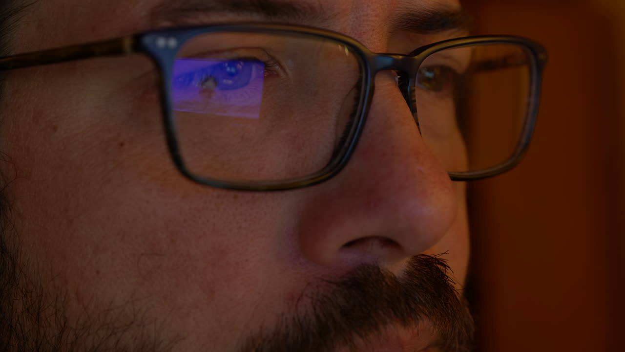 tristes ojos masculinos con anteojos viendo videos de bombas atómicas en la pantalla