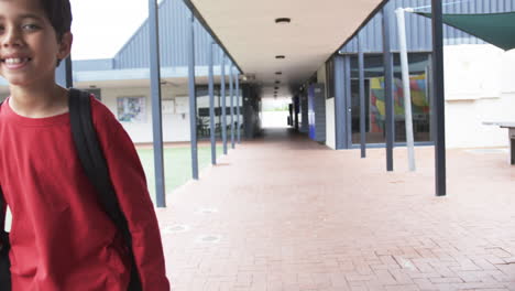 in a school corridor, a young caucasian student smiles brightly with copy space