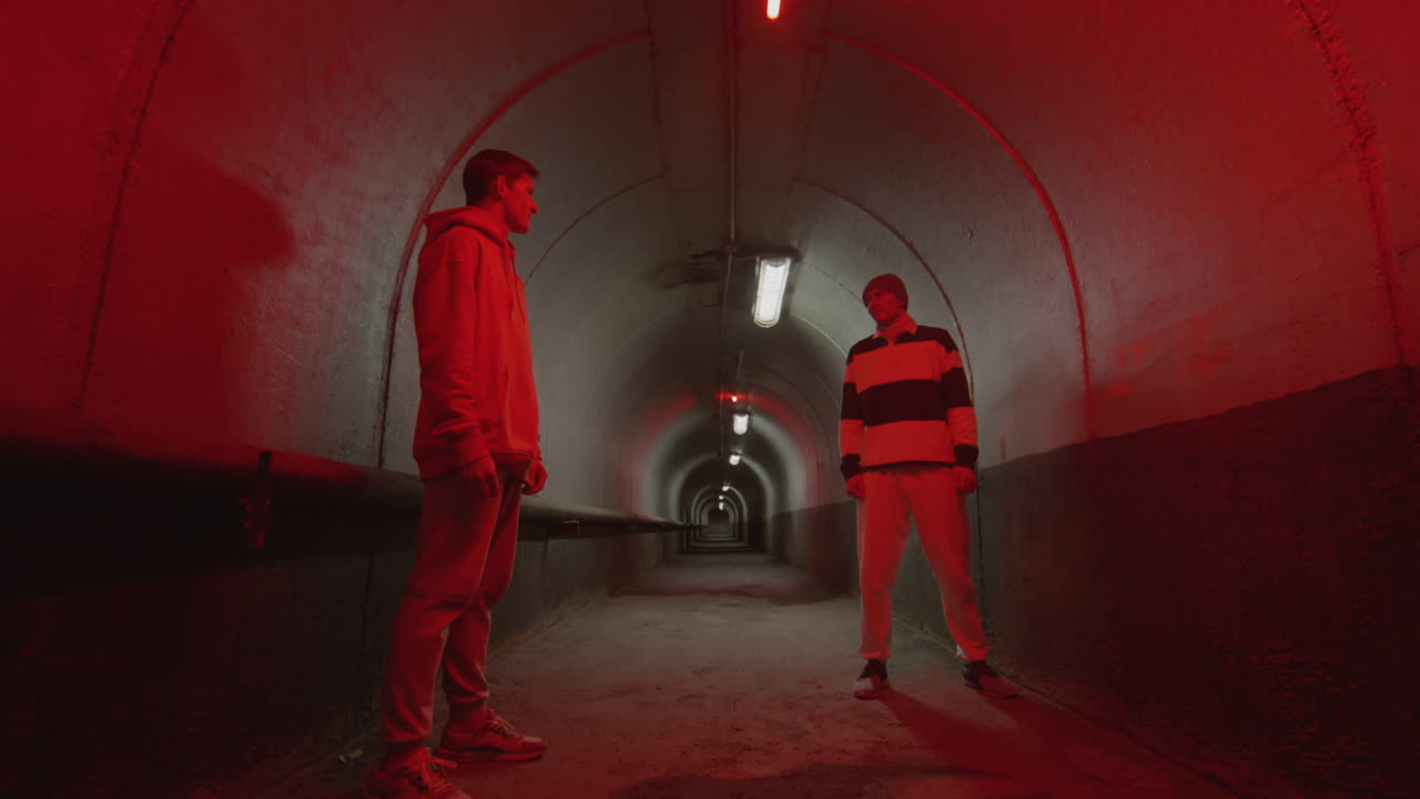 Two Parkourists Standing in Dark Underground Tunnel