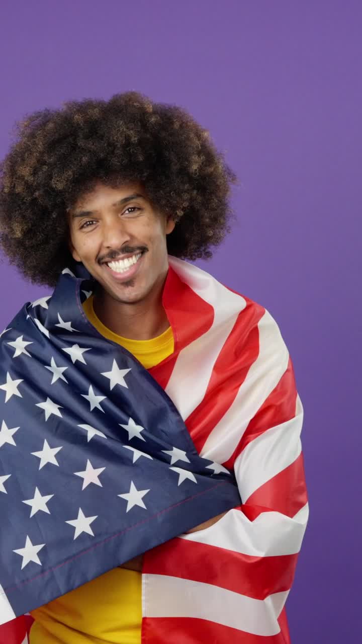 Happy man with curly hair draped in an American flag