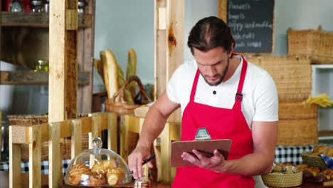 Personal-Masculino-Haciendo-Una-Lista-De-Verificación-En-El-Mostrador-De-La-Panadería.