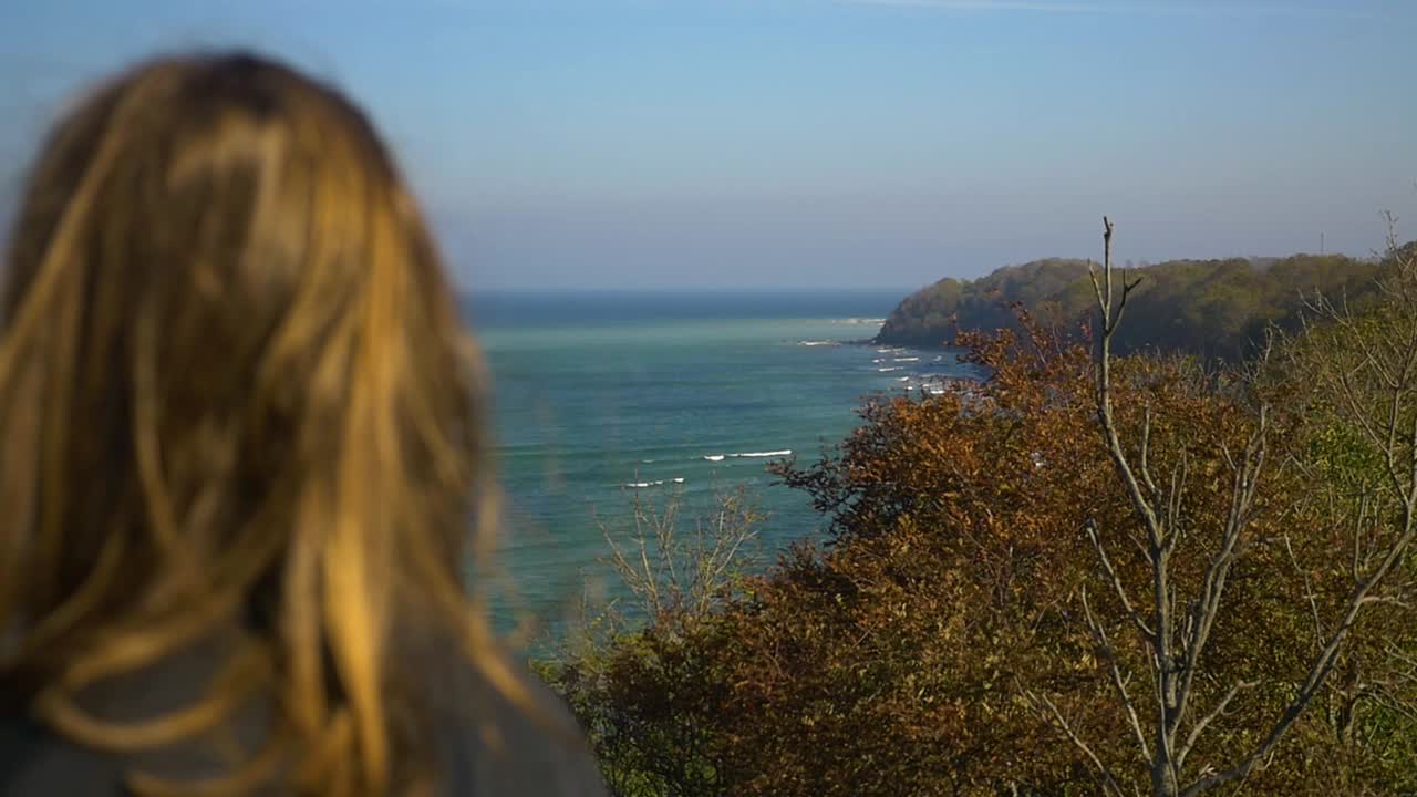 슬로우 모션으로 가을 해안의 바다를 바라보는 소녀