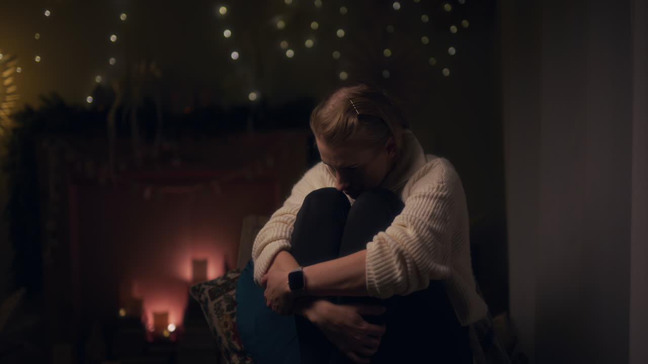 una mujer triste y solitaria se sienta en un sillón por la noche y está herida