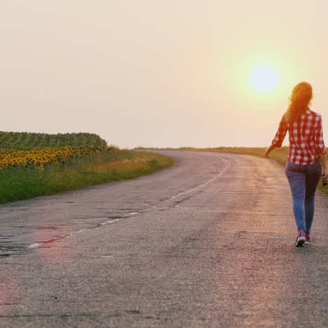 woman walks forward on a rural road at sunset