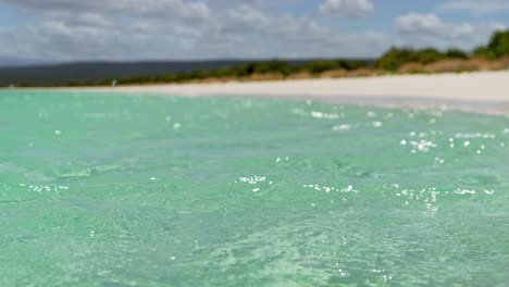 Die-Hand-Der-Frau,-Die-An-Einem-Sonnigen-Tag-Wasser-Im-Ozean-Spielt