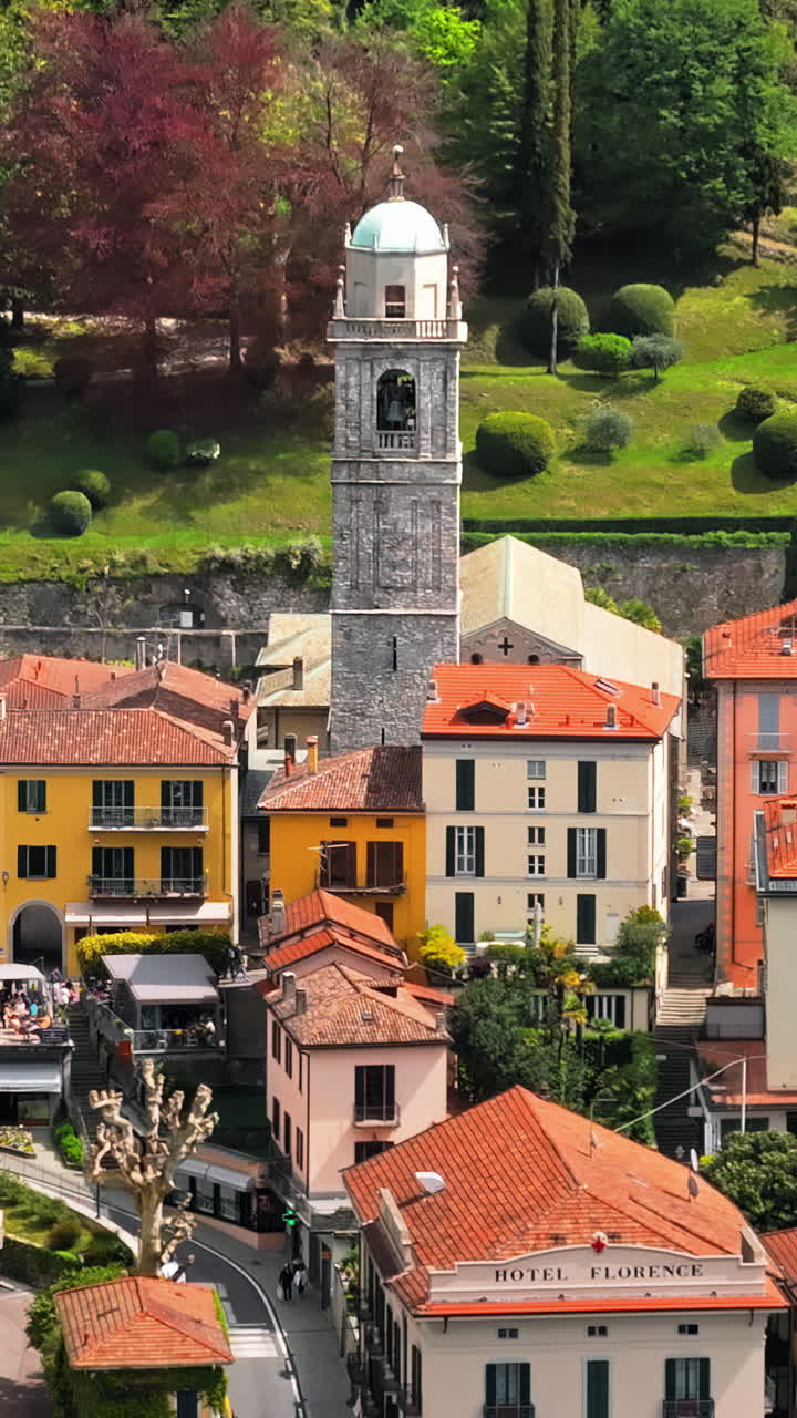 Aerial drone view of the Basilica of St. Giacomo surrounded by houses in Bellagio, Italy. Vertical