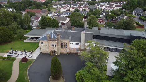 Flight-over-Dalmeny-Park,-a-luxurious-Scottish-country-mansion-and-views-of-the-nearby-town