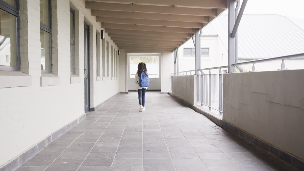 girl walking down school hallway with blue backpack, copy space
