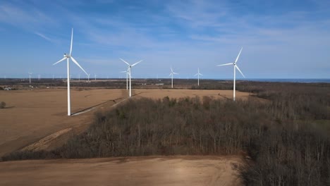 wind turbines in a rural setting with clear skies and forest backdrop, highlighting renewable energy sources, aerial view