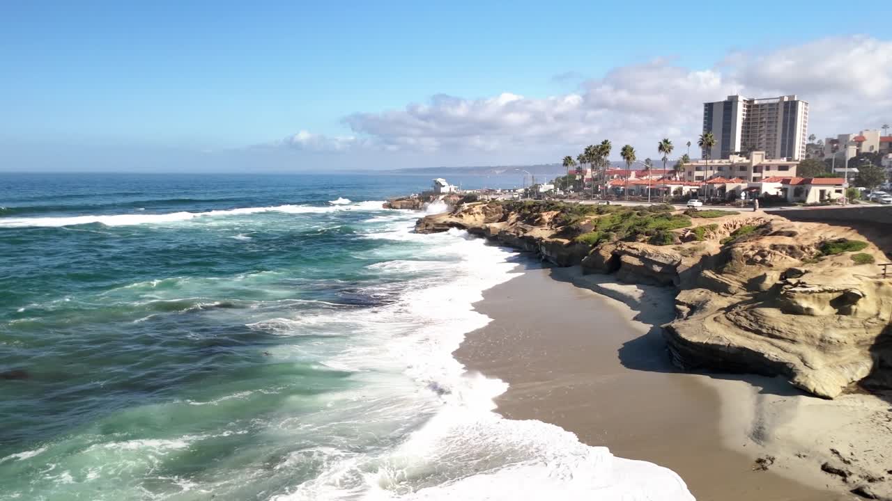 A clean midday drone view featuring rugged rocks and shimmering blue Pacific Ocean water in La Jolla near Torrey Pines and San Diego Ca