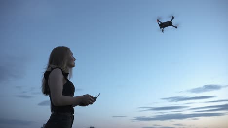 niña joven que controla drones quadcopter volando en el aire con control remoto bajo el cielo azul en el crepúsculo, aviones aéreos no tripulados, concepto de tecnología moderna