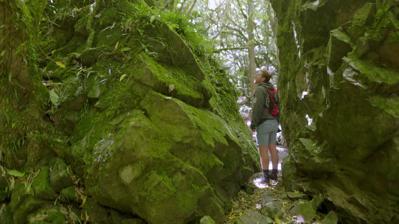 un video clip de un hombre caminando a través de varias piedras grandes que están cubiertas de rocas