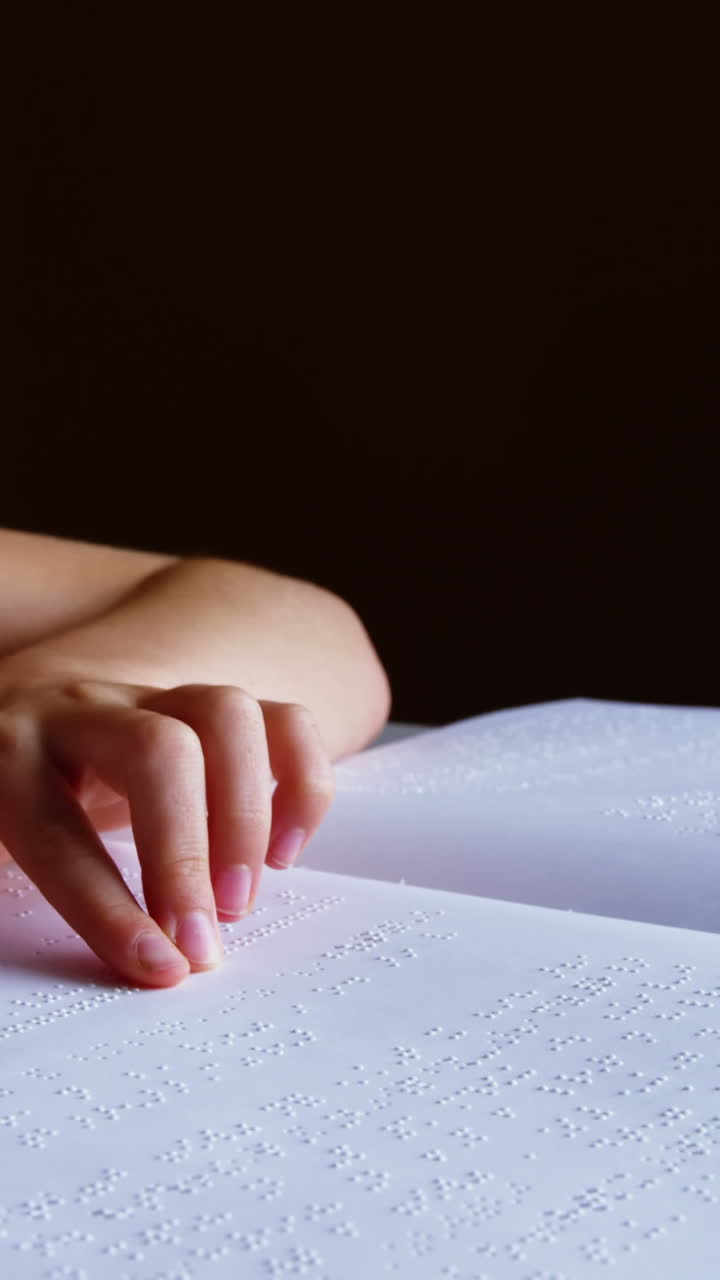 Schoolgirl reading a braille book in classroom