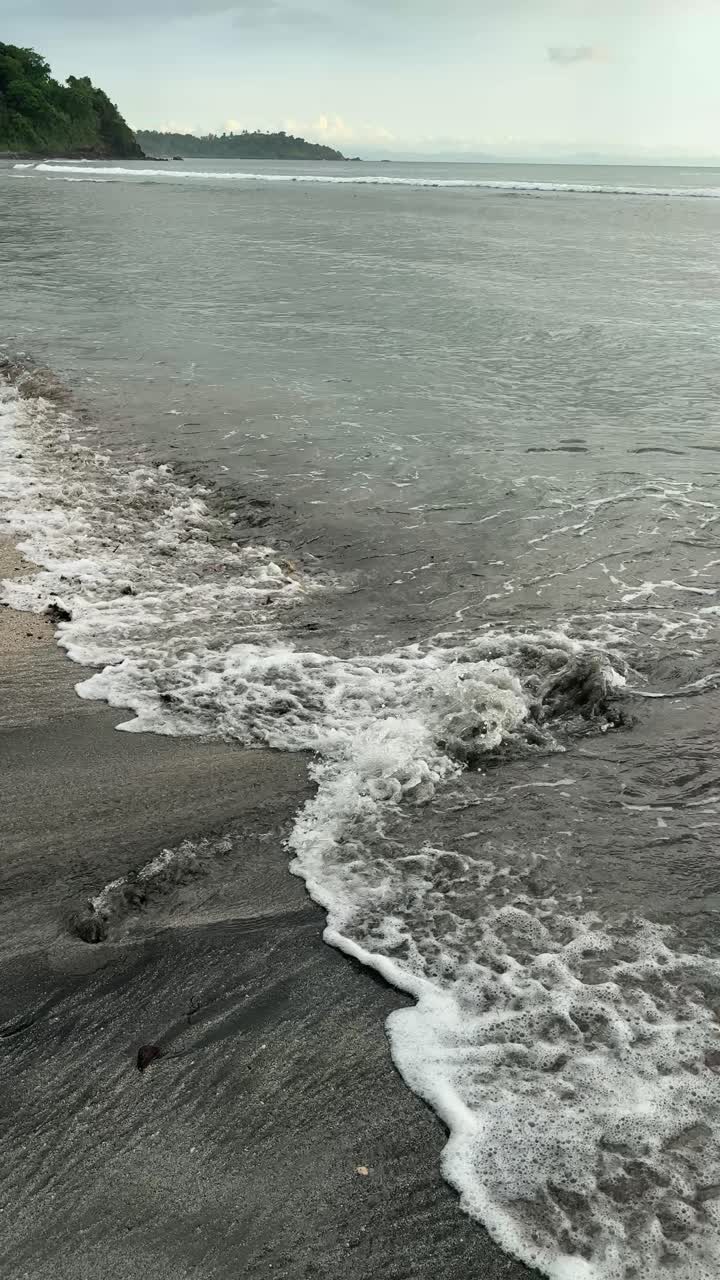 Dolci onde dell'oceano che lambiscono una spiaggia di sabbia scura