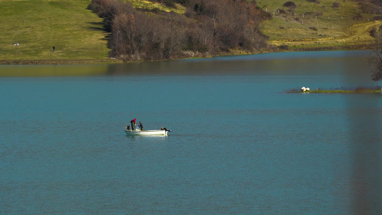 산속 호수에서 물고기로 그물을 모으는 하얀 배로 낚시하는 어부들