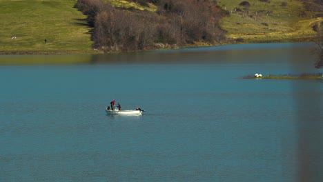 fishermen fishing by white boat collecting the net with fish on mountain lake