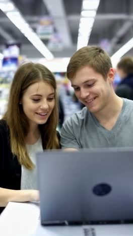 young couple looking at a laptop in an electronics store