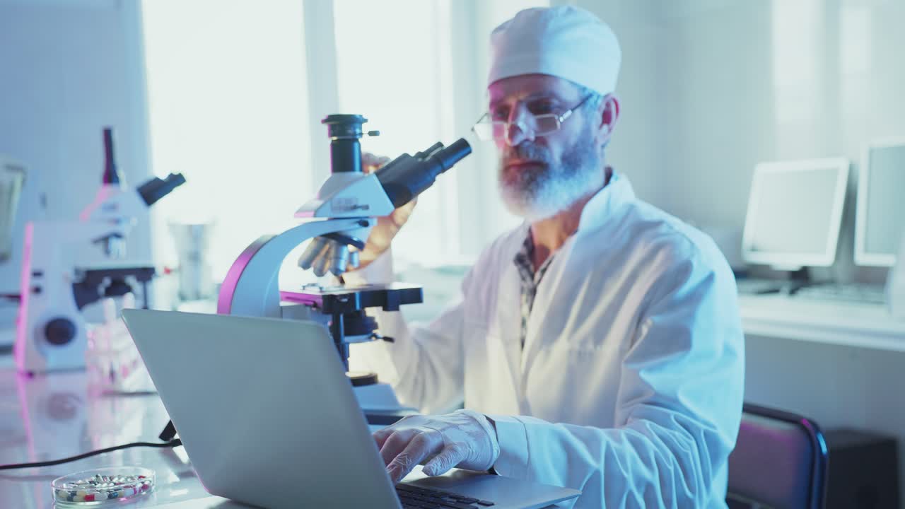 Focused Scientist Working with Microscope and Laptop in Modern Laboratory