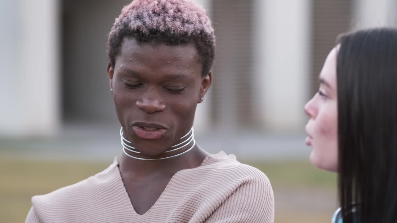Transgender man and a woman talking and laughing while sitting outdoors